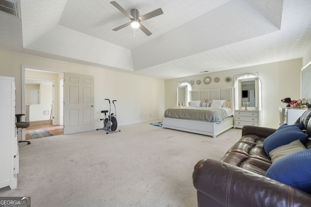 bedroom featuring ceiling fan, light carpet, and a raised ceiling