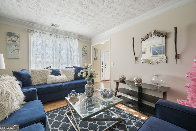 living room with hardwood / wood-style flooring, a textured ceiling, and ornamental molding