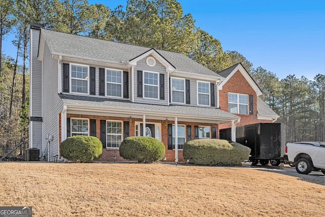 view of front facade featuring covered porch, a front lawn, and central AC