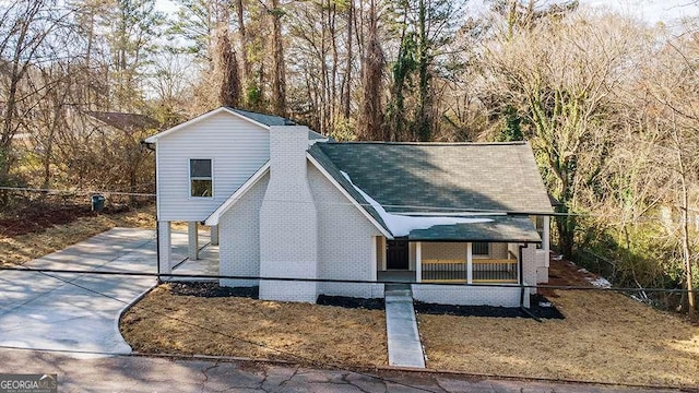 view of front facade with brick siding, a porch, and a shingled roof