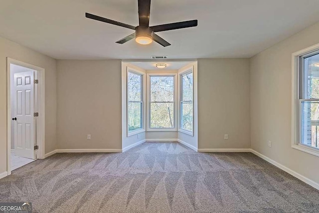 empty room featuring baseboards, carpet flooring, ceiling fan, and plenty of natural light
