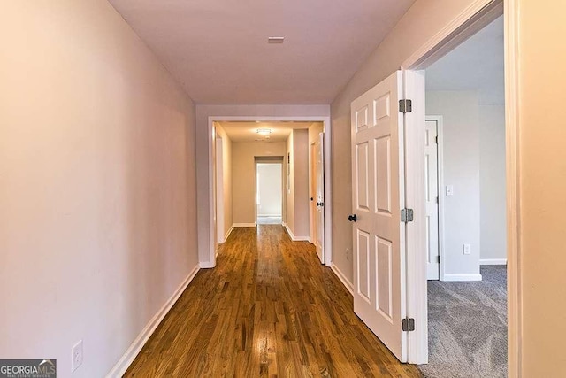 hallway featuring dark wood-type flooring and baseboards