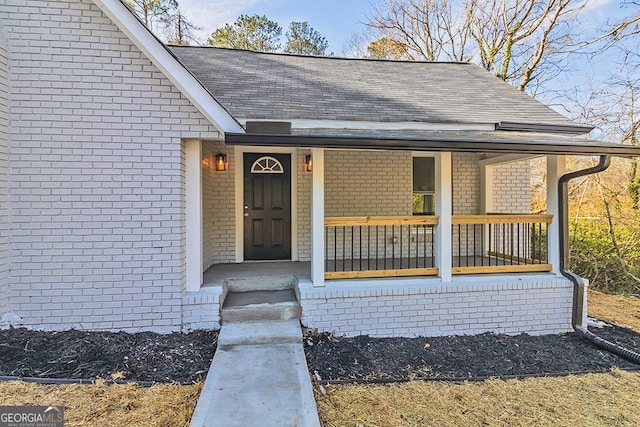 view of exterior entry featuring a porch and brick siding