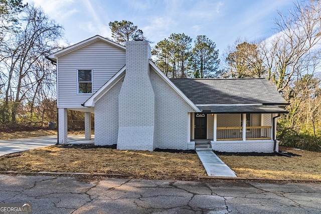 view of front of home with a chimney, brick siding, a carport, and driveway