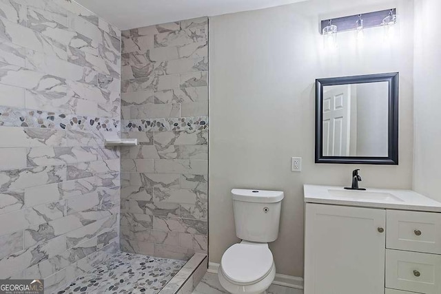 bathroom with toilet, vanity, and a tile shower