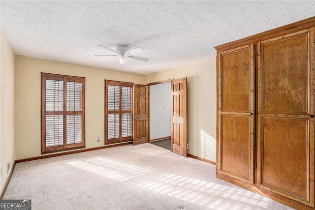 unfurnished bedroom with light carpet, ceiling fan, and a textured ceiling