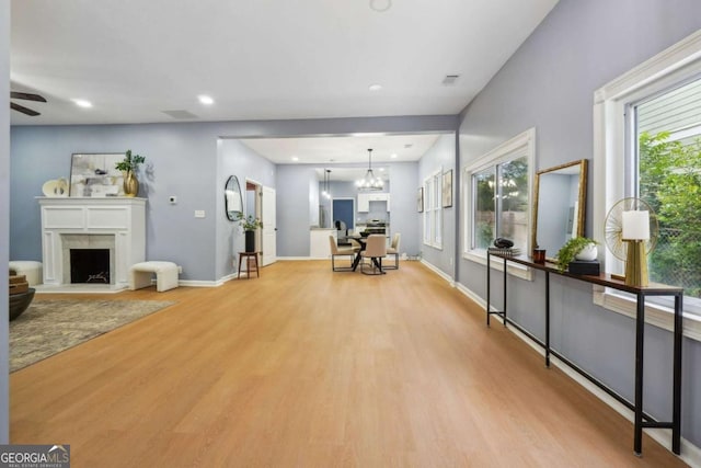 interior space featuring a wealth of natural light, ceiling fan with notable chandelier, and light hardwood / wood-style flooring