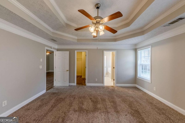 unfurnished bedroom with ceiling fan, ornamental molding, carpet flooring, and a tray ceiling