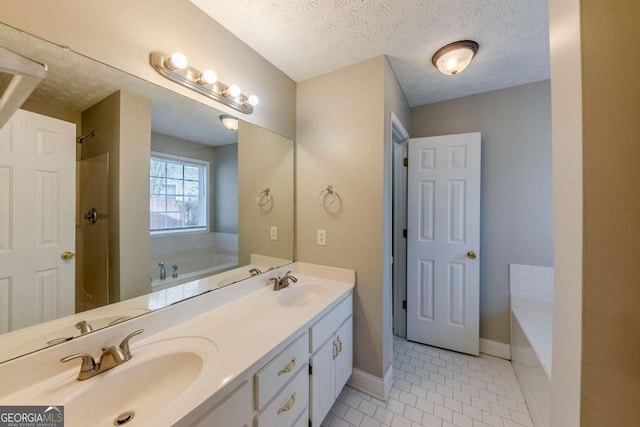 bathroom with a textured ceiling, tile patterned floors, a bathtub, and vanity