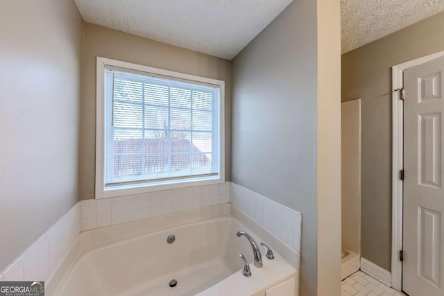 bathroom with tile patterned floors, a textured ceiling, and a bath