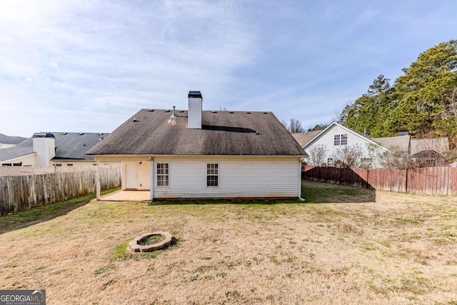 back of property featuring a patio area, a fire pit, and a lawn