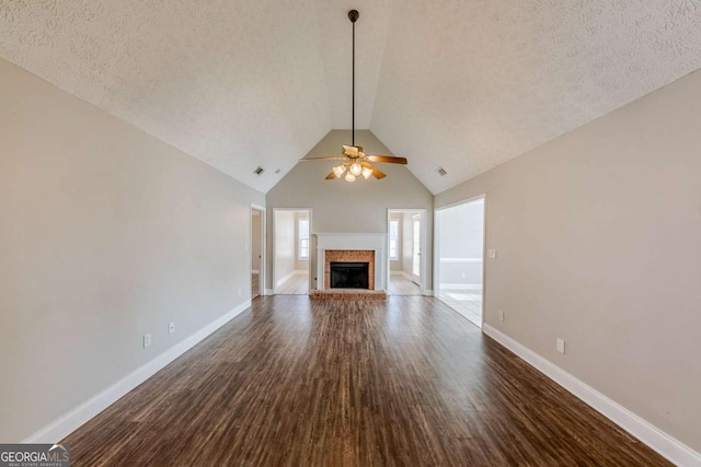 unfurnished living room featuring lofted ceiling, ceiling fan, dark hardwood / wood-style floors, and a textured ceiling