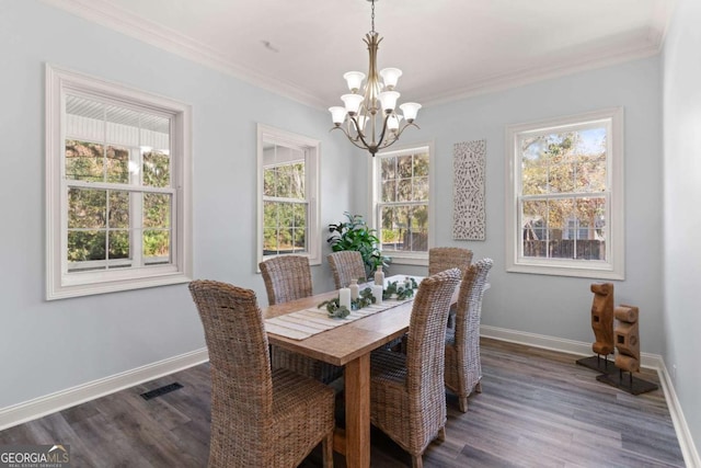 dining space featuring dark wood-type flooring, an inviting chandelier, and ornamental molding