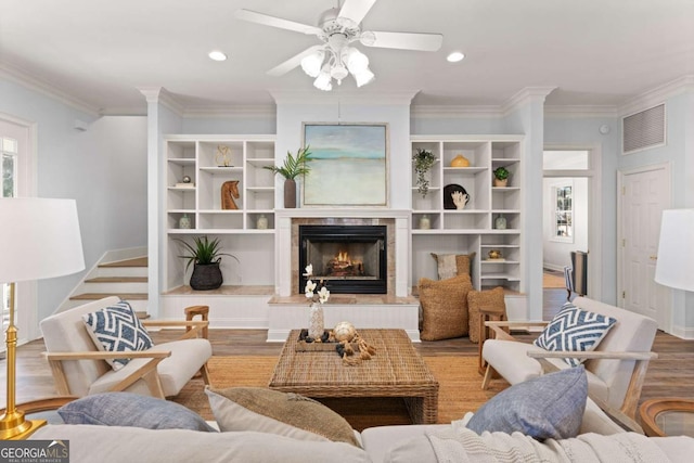 living room featuring light hardwood / wood-style floors, crown molding, ceiling fan, and a fireplace