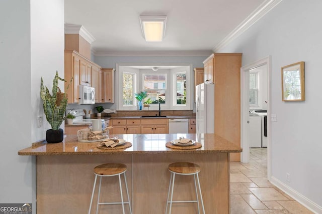 kitchen with kitchen peninsula, washing machine and dryer, white appliances, and light stone counters