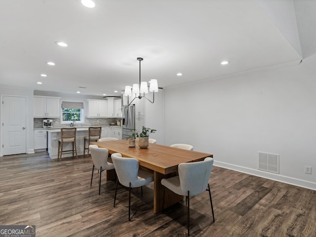 dining room with crown molding, dark hardwood / wood-style floors, and an inviting chandelier