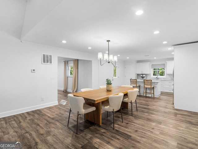 dining room featuring crown molding, dark hardwood / wood-style floors, sink, and an inviting chandelier