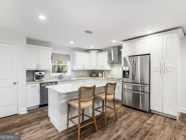 kitchen featuring a center island, sink, white cabinetry, stainless steel appliances, and wall chimney exhaust hood