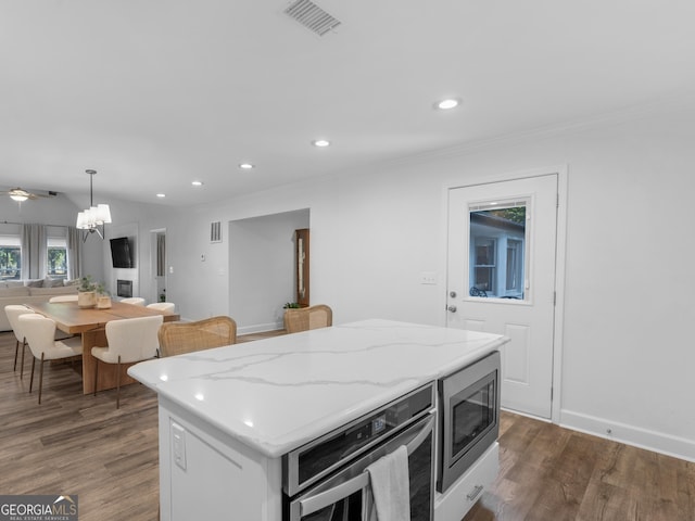 kitchen with pendant lighting, white cabinets, a kitchen island, dark hardwood / wood-style floors, and stainless steel microwave