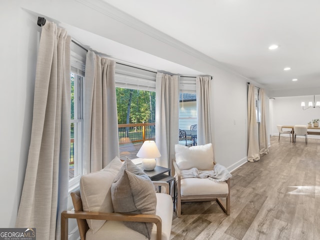 sitting room featuring light hardwood / wood-style floors, ornamental molding, and a notable chandelier