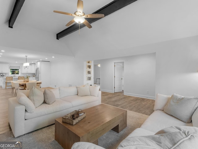 living room featuring ceiling fan, vaulted ceiling with beams, and light wood-type flooring