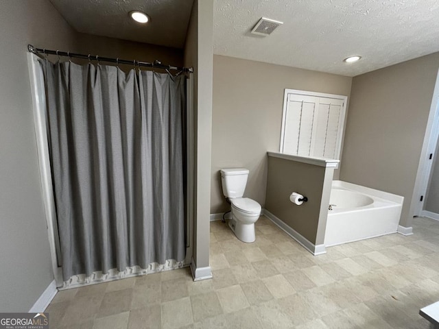 bathroom featuring toilet, a bathing tub, and a textured ceiling