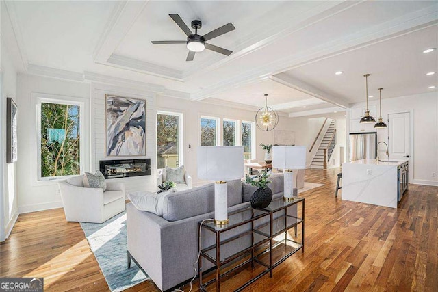 living room featuring a wealth of natural light, crown molding, light wood-style flooring, and stairs