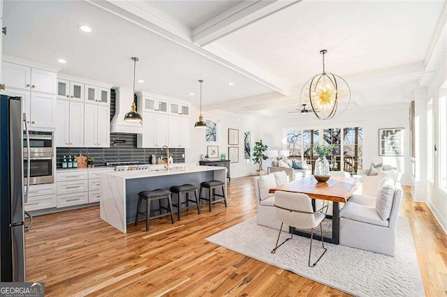 interior space featuring white cabinets, hanging light fixtures, beam ceiling, and decorative backsplash