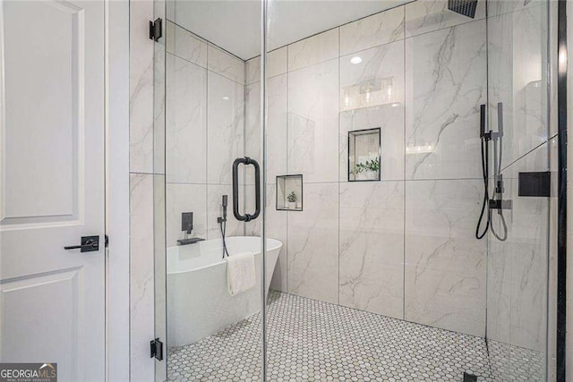 full bath featuring a stall shower, a freestanding bath, and tile walls