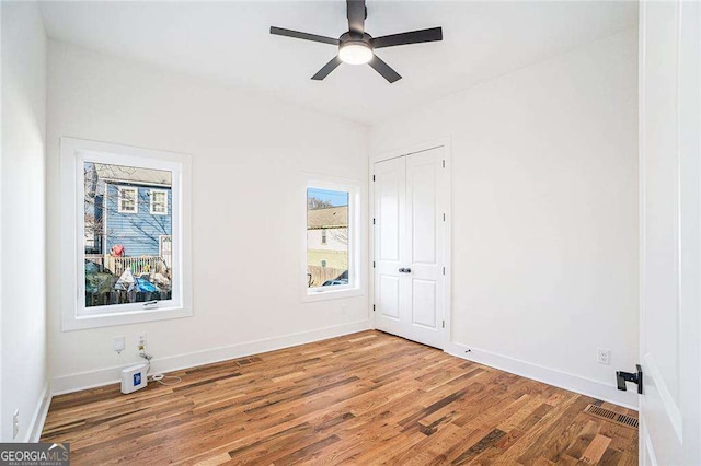 unfurnished bedroom with a ceiling fan, baseboards, visible vents, and wood finished floors