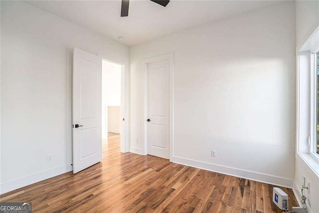 unfurnished bedroom featuring a ceiling fan, visible vents, baseboards, and wood finished floors