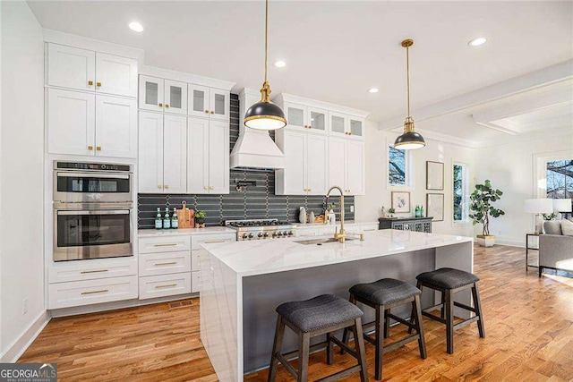 kitchen featuring glass insert cabinets, appliances with stainless steel finishes, white cabinets, and a sink