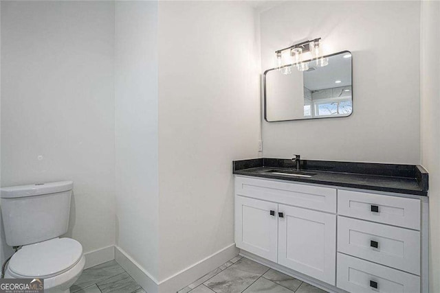 bathroom featuring marble finish floor, baseboards, vanity, and toilet