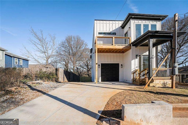 view of front of home with an attached garage, a balcony, fence, driveway, and board and batten siding