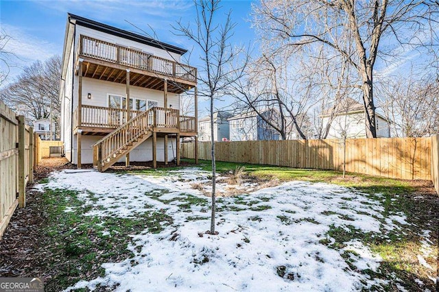 snow covered property with a deck, a fenced backyard, and stairway