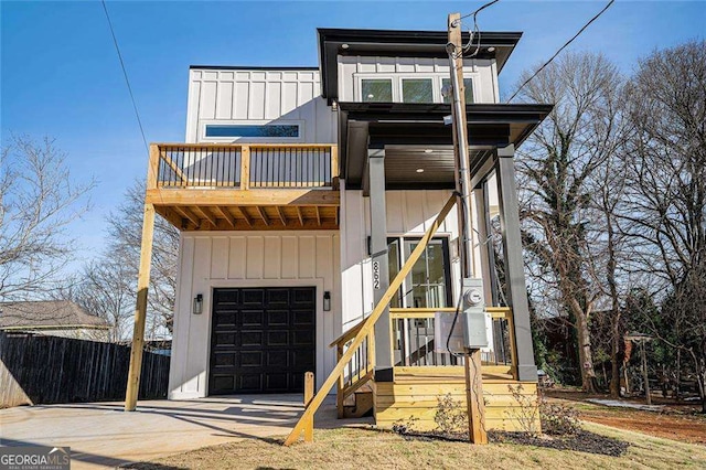 view of front of property with concrete driveway, an attached garage, board and batten siding, fence, and a balcony