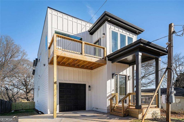 view of front facade featuring board and batten siding, fence, a balcony, and an attached garage