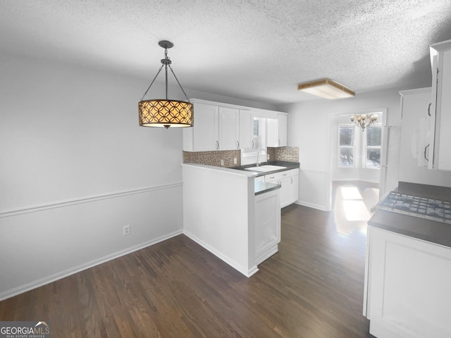 kitchen featuring white cabinets, decorative light fixtures, dark wood-type flooring, tasteful backsplash, and sink