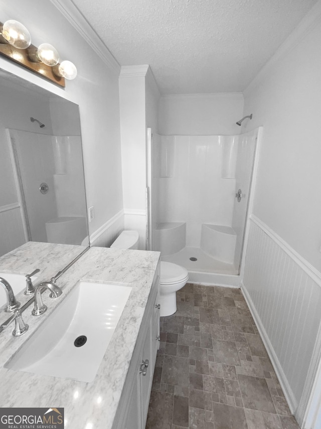 bathroom featuring toilet, vanity, a shower, a textured ceiling, and ornamental molding