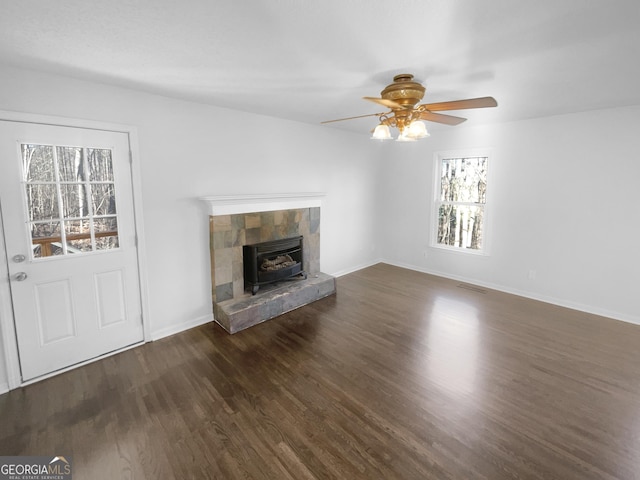 unfurnished living room with dark wood-type flooring, ceiling fan, and a tiled fireplace