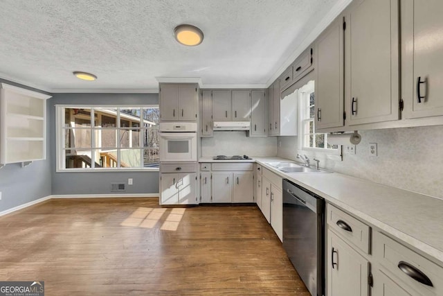 kitchen featuring hardwood / wood-style floors, decorative backsplash, dishwasher, oven, and sink