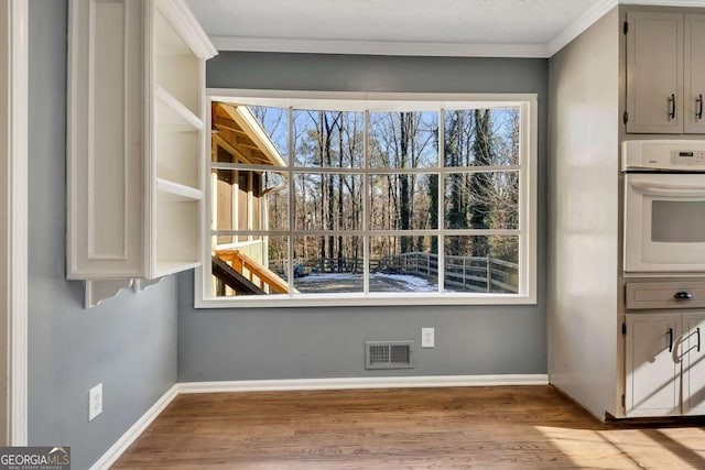 unfurnished dining area featuring ornamental molding and light hardwood / wood-style floors