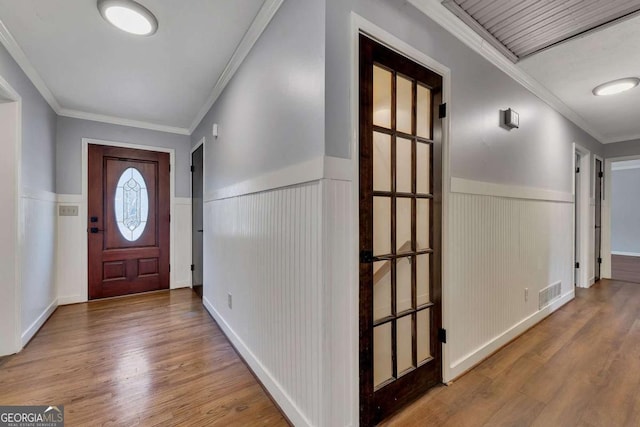 foyer with ornamental molding and hardwood / wood-style floors