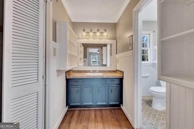 bathroom featuring wood-type flooring, toilet, vanity, and ornamental molding