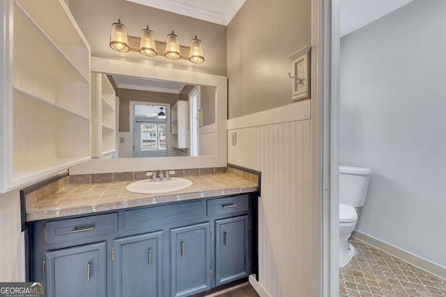 bathroom with toilet, vanity, and ornamental molding