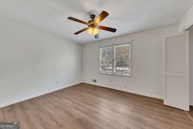 unfurnished bedroom featuring ceiling fan, a closet, a textured ceiling, and light hardwood / wood-style floors