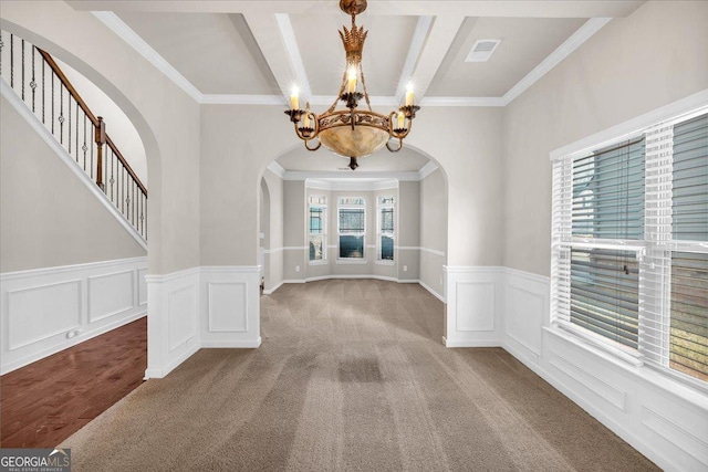 spare room featuring an inviting chandelier, crown molding, and carpet floors