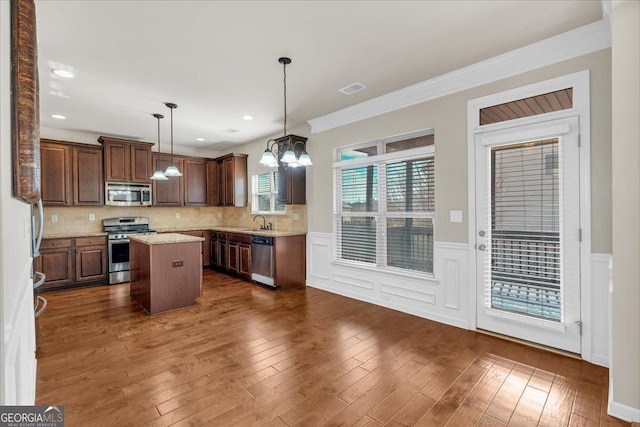 kitchen featuring appliances with stainless steel finishes, a center island, sink, and backsplash