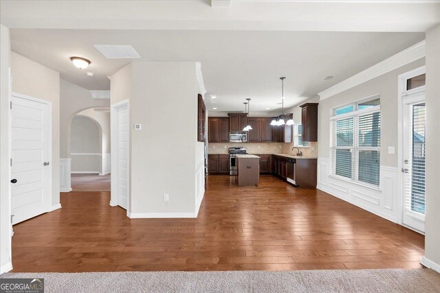 unfurnished living room with ceiling fan with notable chandelier, a fireplace, carpet flooring, crown molding, and beam ceiling