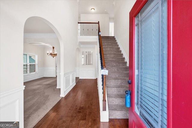 entryway with dark wood-type flooring, crown molding, and a chandelier